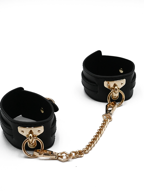 Black faux leather handcuffs with gold chain and hardware